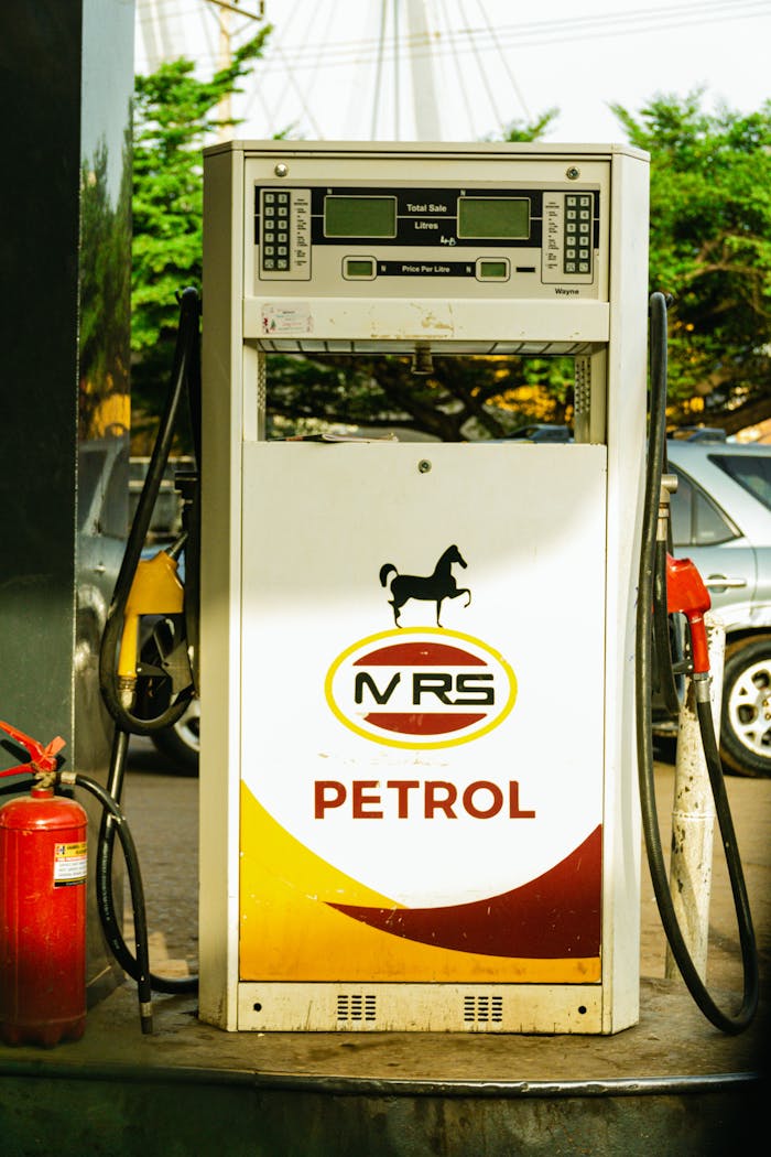A petrol pump dispenser at a gas station with visible signage and fire extinguisher.